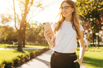 Image of woman's hand holding mobile phone outdoors