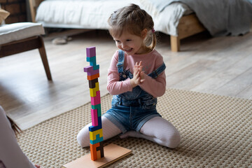 Kids playing with wooden blocks laying on the floor in their room.