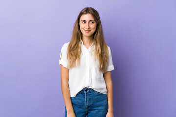 Young woman over isolated purple background having doubts while looking side