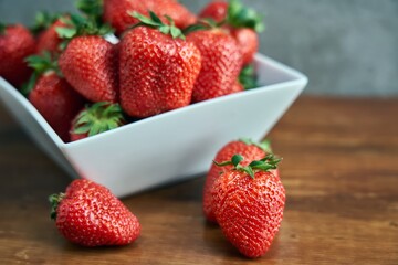 Strawberries in white bowl on wooden table. Close up of fress red strawberries.