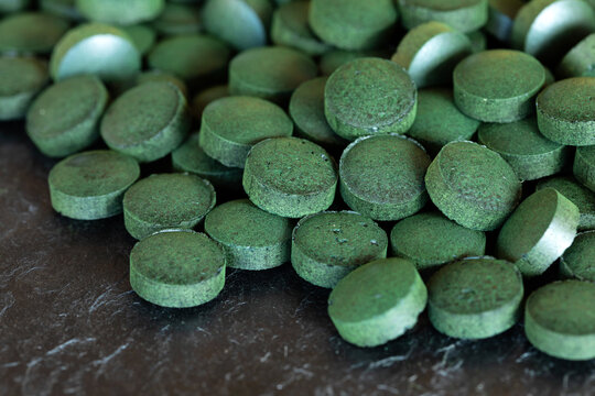 Spirulina green pills on slate plate