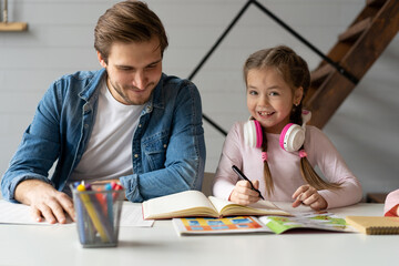 A father helping his little daughter to do her homework for the school - Powered by Adobe