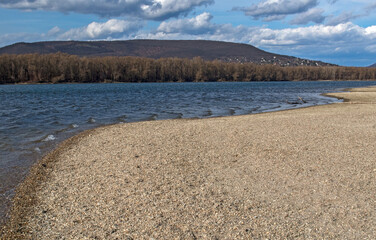 On the river bank on a spring sunny day with rippling water mirror in the wind	