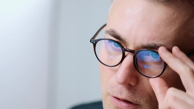 A close-up view of a concentrated businessman wearing glasses is working with his computer sitting in the office