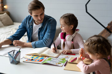 A father helping his little daughter to do her homework for the school