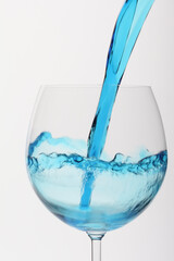Blue liquid being poured into wine  glass container