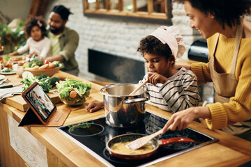 African American son assisting mother in preparing food in the kitchen.
