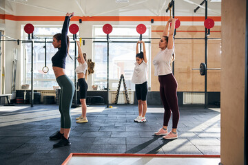 Four lovely ladies standing tall and stretching at gym