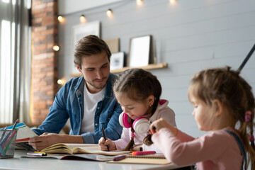 Fototapeta premium A father helping his little daughter to do her homework for the school