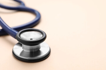 Stethoscope on beige background, closeup. Space for text