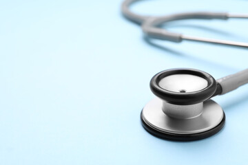 Stethoscope on light blue background, closeup. Space for text
