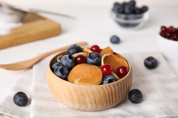 Delicious mini pancakes cereal with berries served on table