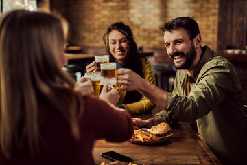 Happy man toasting with his friends while drinking beer in a pub.