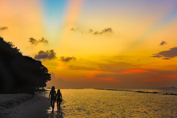 silhouette of two women walking on the beach at sunset