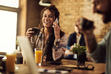 Young happy woman talking on the phone while relaxing in a cafe.