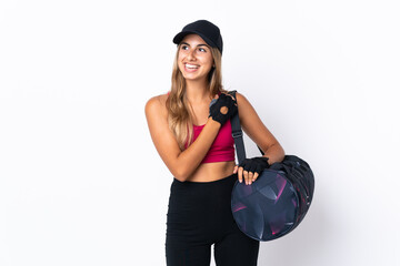 Young sport woman with sport bag over isolated white background looking up while smiling