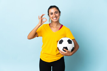 Young hispanic football player woman over isolated on blue background showing ok sign with fingers