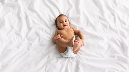 Cute little African American baby lying on bed at home