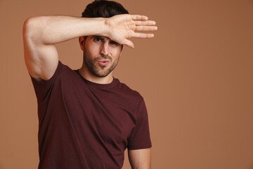 Displeased young man with headache touching his forehead