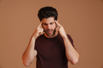 Displeased young man with headache rubbing his temples