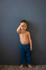Fototapeta na wymiar a small boy in blue jeans on a dark background 