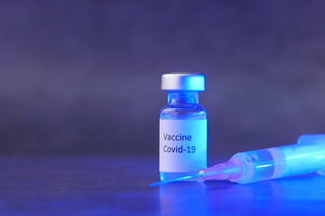 Close up of coronavirus vaccine and syringe on black background