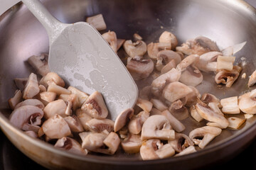 Mushrooms are fried in a pan, the spatula mixes them