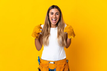 Young hispanic electrician woman over isolated yellow wall celebrating a victory in winner position
