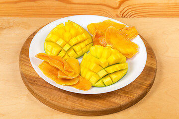 Dried mango slices and fresh cut mango halves on dish