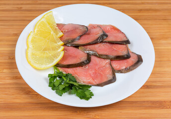 Slices of smoked pink salmon with lemon and parsley twig