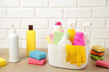 Full box of cleaning supplies and gloves on white wall.