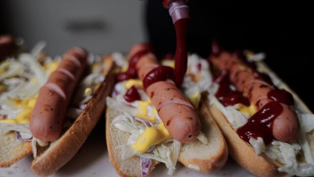 pour red sauce over sausage in hot dog