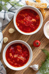 Homemade Traditional Ukrainian beet soup with fresh green dill. Russian borscht in bowl of tomatoes, sour cream, and mushrooms on white background