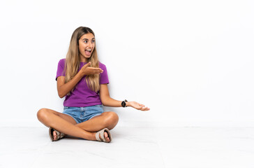 Young hispanic woman sitting on the floor with surprise expression while looking side
