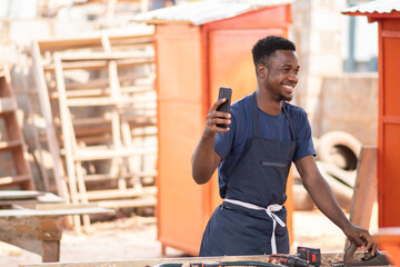 african carpenter smiling while using his phone for video call