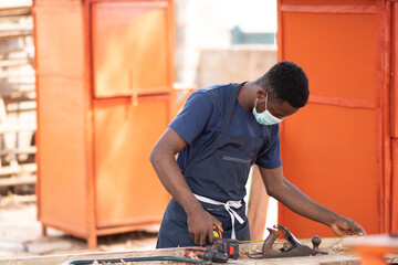 african carpenter working, wearing a face mask