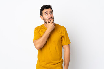 Young handsome man with beard isolated on white background having doubts and with confuse face expression
