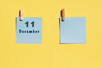 11 December. 11th day of the month, calendar date. Two blue sheets for writing on a yellow background. Top view, copy space. Winter month, day of the year concept