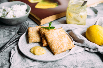 Crepes with homemade cottage cheese and lemon curd on a gray plate