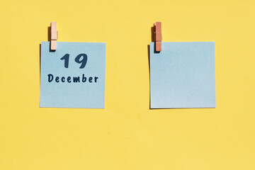 19 December. 19th day of the month, calendar date. Two blue sheets for writing on a yellow background. Top view, copy space. Winter month, day of the year concept