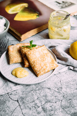 Crepes with homemade cottage cheese and lemon curd on a gray plate