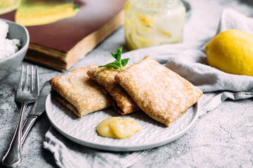 Crepes with homemade cottage cheese and lemon curd on a gray plate
