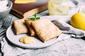 Crepes with homemade cottage cheese and lemon curd on a gray plate