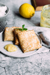 Crepes with homemade cottage cheese and lemon curd on a gray plate