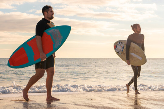 Men with skimboards in a beautiful orange sunset on the beach. Palma de Mallorca, Spain