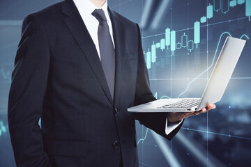 Investing market exchange concept with laptop in businessman hand on digital screen with financial chart candlestick background