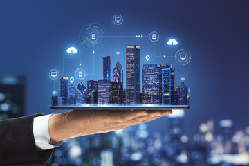 Smart city concept with real skyscrapers layout with glowing digital cloud technology icons on digital tablet screen that carrying businessman hand on megapolis city background