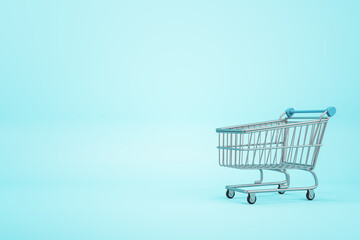 Online shopping concept with empty supermarket shopping cart on blue blank backdrop. Mockup