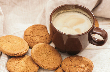 A cup of aromatic coffee cappuccino with Oatmeal cookies. Morning rays and latte for breakfast in a beautiful brown cup. Wooden background.