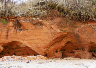 Sea cliff with Devonian sandstone outcrops. During the storm, niches and caves were washed away in the sandstones, sandstone columns were formed